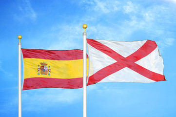 Spain and Northern Ireland two flags on flagpoles and blue cloudy sky