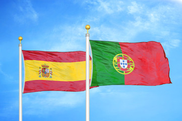 Spain and Portugal two flags on flagpoles and blue cloudy sky
