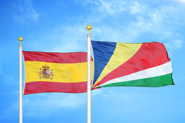 Spain and Seychelles two flags on flagpoles and blue cloudy sky