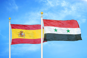 Spain and Syria two flags on flagpoles and blue cloudy sky