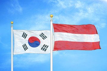 South Korea and Austria  two flags on flagpoles and blue cloudy sky