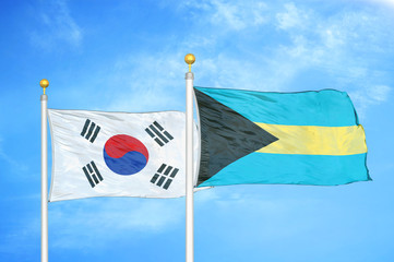 South Korea and Bahamas  two flags on flagpoles and blue cloudy sky