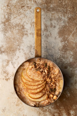 Porridge with Apple Slices and Granola in Copper Saucepan Top View