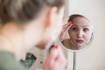 Cosmetic face mask and girl look in the mirror