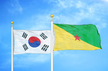 South Korea and French Guiana two flags on flagpoles and blue cloudy sky