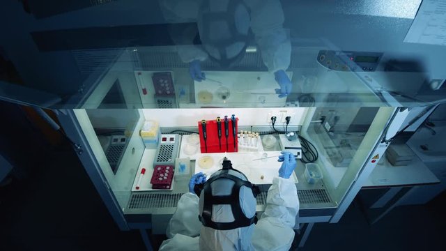 Person in protection suit works in laboratory, creating a coronavirus vaccine. Coronavirus, covid-19, virus research concept.