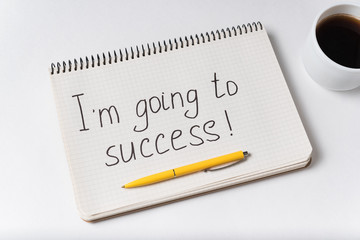 Im going to success notice. Notebook pen and cup of coffee on white background.