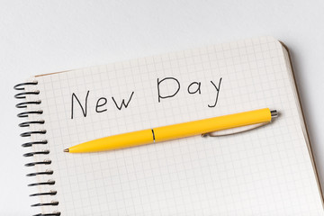 Close-up of Notepad with words NEW DAY and pen. Handwritten inscription in notebook