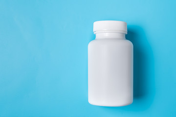 White medicine plastic package for pills. Bottle mockup on a blue background. Copy space