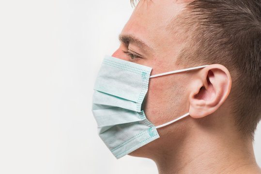 Adult man in medical mask. Portrait side view on white background. Health care and medical concept.