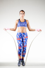 girl in sports outfit jumping with rope