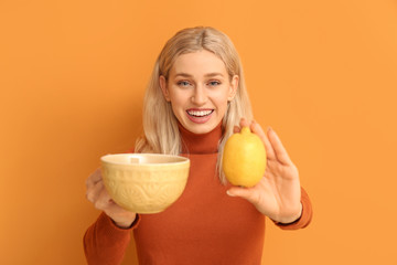 Beautiful young woman with tea and lemon on color background