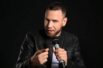 Male singer with microphone on dark background