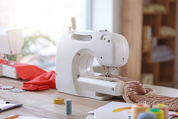 Modern sewing machine on table in tailor's workshop