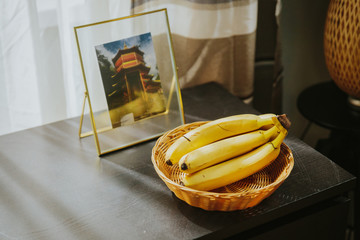 ripe bananas in a basket on a shelf near the picture. © Lauris Aizupietis