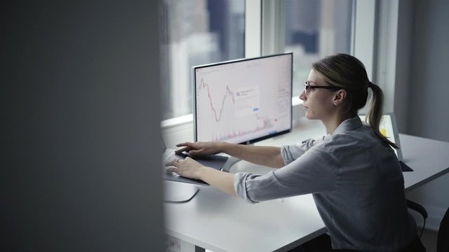 Caucasian female employee checking data analytic while testing trade security of platform website with financial infographics, intelligent administrator browsing online page with chart graphs
