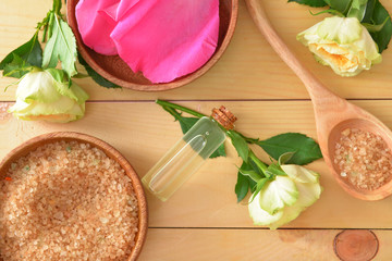 Bottle of rose essential oil and sea salt on table