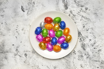 Plate with sweet chocolate eggs on light background