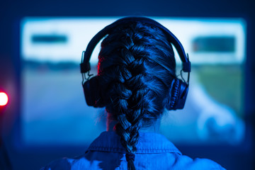 Gamer plays a video game. Girl with a joystick and headphones in a neon room at night. Online...