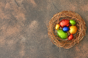 Fototapeta na wymiar Nest with sweet chocolate eggs on grey background