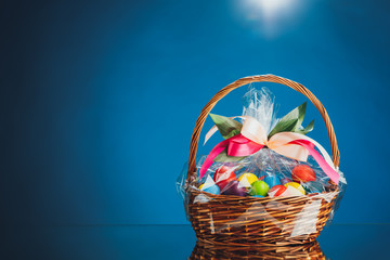 Easter gift basket with multicolor eggs, blue background