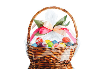 Easter gift basket with multicolor eggs, isolated on white