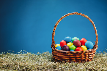 Easter basket with multicolor eggs, blue background