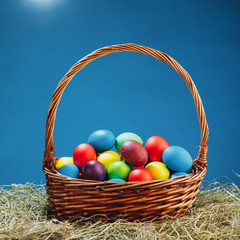 Easter basket with multicolor eggs, blue background
