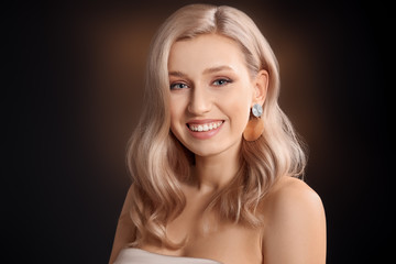 Young blonde with beautiful hair on dark background