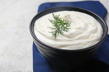 Bowl of tasty sour cream on light table