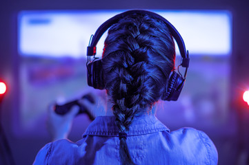 Young girl plays online computer games with gamers at night. Gaming communication, tournaments,...