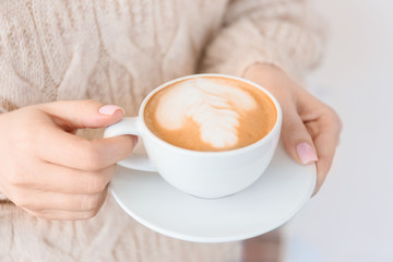 Woman with cup of tasty cappuccino outdoors, closeup