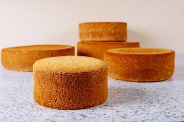 Different sizes sponge cakes on table.
