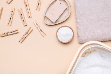 Soap, clothes pegs, towel and laundry detergent on color background