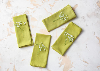 Napkins with floral decor prepared for table setting on light background