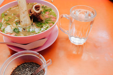 Bone marrow soup also known as soup gear box.served in a pink bowl. The glass contain word TAHAN PANAS or hot resistant
