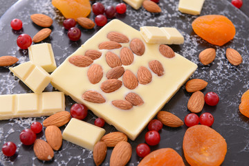 Sweet white chocolate with nuts and dried fruit on table