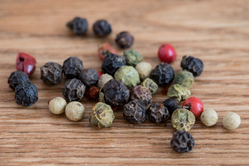 Variety of peppercorns on a wooden service.