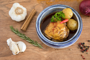 Curry chicken dish with vegetables.  Dinner presented in a bowl on a wooden surface, decorated with spices and herbs.