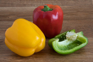 Yellow, red and green peppers on a wooden background.