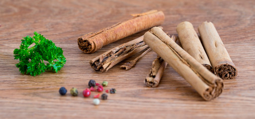 Cinnamon sticks, parsley and pepper corns on a wooden service.  