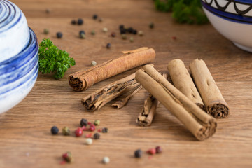 Cinnamon sticks, parsley and pepper corns on a wooden service.  