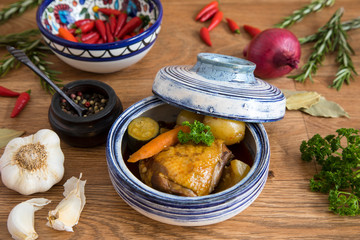 Curry chicken dish with vegetables.  Dinner presented in a bowl on a wooden surface, decorated with spices and herbs.