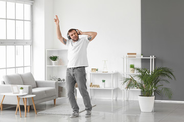 Handsome young man dancing and listening to music at home