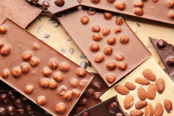 Different sweet chocolate with nuts as background