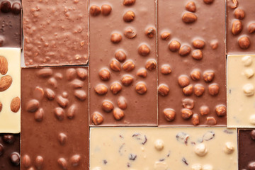 Different sweet chocolate with nuts as background