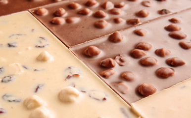 Different sweet chocolate with nuts as background