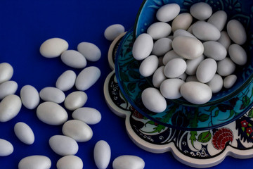 Traditional Turkish Hard,Almond Candies designed in ceramic candy bowl on  blue surface.The Sugar Feast after Ramadan