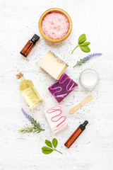 Top view of organic soaps and cosmetics arranged with lavender, herbs, chia seeds and essential oils. White rusric background.