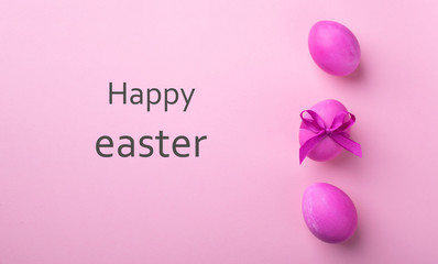 Bright pink eggs with satin bow text Happy Easter on a pink background. Festive spring concept. Color trend. Minimalism